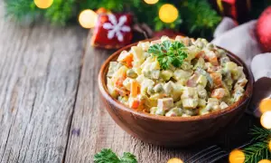 Sałatka jarzynowa z idealnie ugotowanymi ziemniakami, marchewką i groszkiem, udekorowana natką.