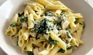 Penne z kurczakiem, szpinakiem i fetą, posypane parmezanem. Pyszne danie, które zachwyci każdego.