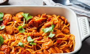Pyszne spaghetti z kiełbasą w sosie pomidorowym, udekorowane kolendrą. Idealny pomysł, co zrobić z makaronem spaghetti na szybki obiad.