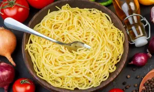 Porcja makaronu spaghetti w drewnianej misce, gotowa do podania. Trudno określić, ile cm ma makaron spaghetti, ale wygląda na idealnie ugotowany.
