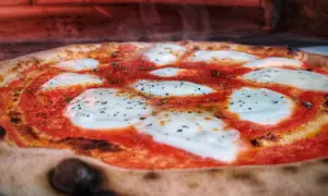 Gorąca pizza z ciągnącym się serem i sosem pomidorowym. Czy pizza jest ciężkostrawna? Zależy od składników i sposobu przygotowania.