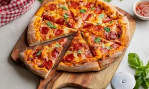 Pyszna pizza z pepperoni, z ciągnącym się serem i świeżą bazylią, podana na drewnianej desce.