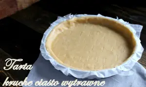 Surowe ciasto kruche wytrawne na tartę, przygotowane do pieczenia. Widelcem nakłute dno i boki.
