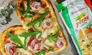 Serce z pizzy z rukolą i szynką, obok mąka do pizzy. Idealne do pieczenia pizzy w piekarniku.