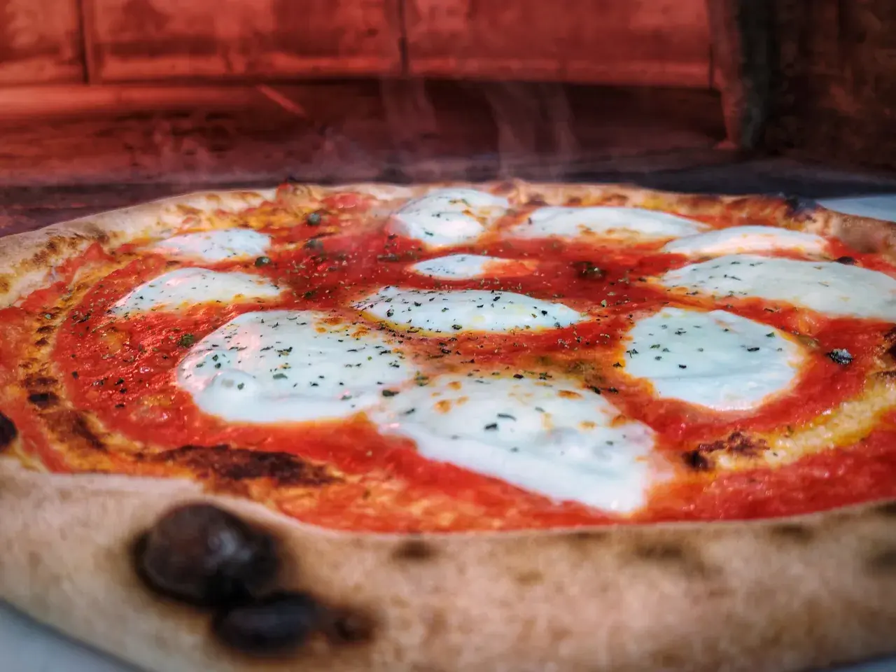 Gorąca pizza z ciągnącym się serem i sosem pomidorowym. Czy pizza jest ciężkostrawna? Zależy od składników i sposobu przygotowania.