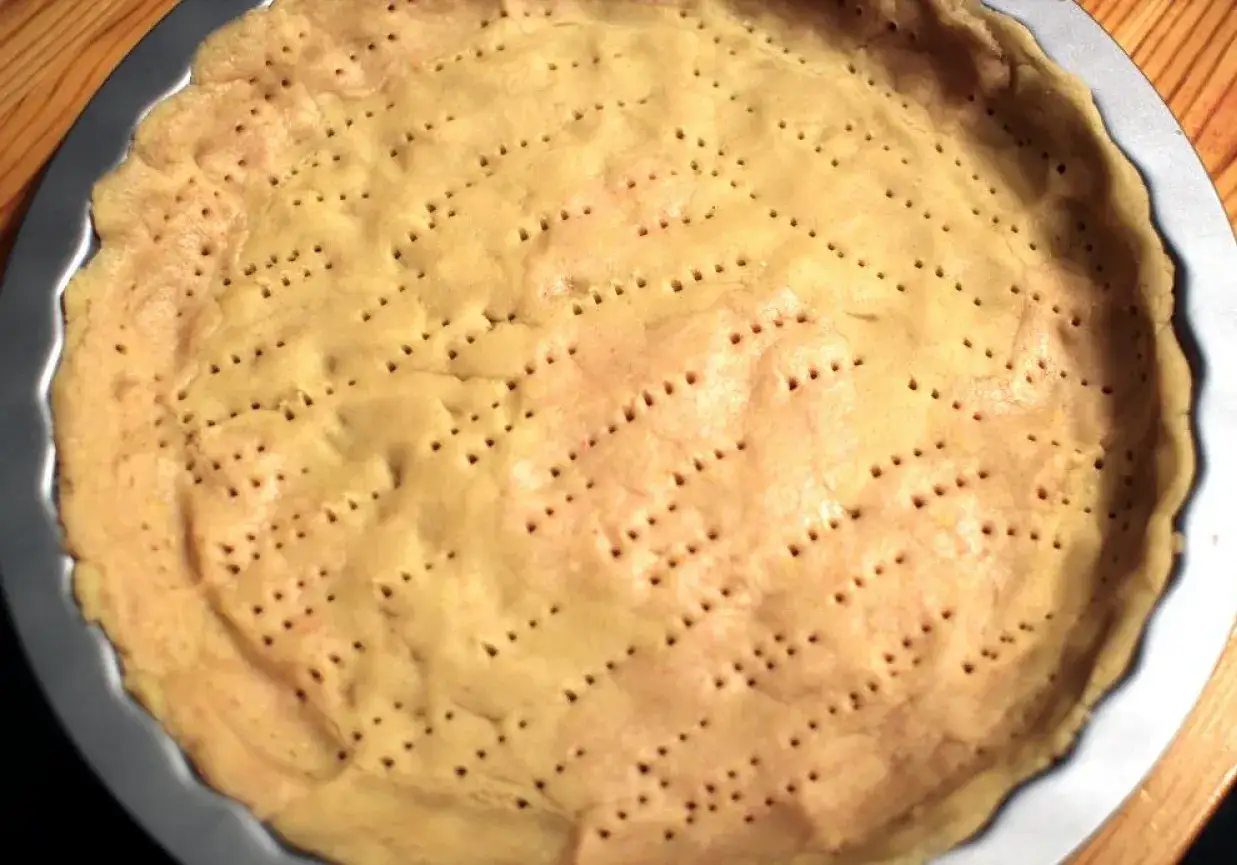 Gotowy do pieczenia spód do tarty na słodko, z licznymi dziurkami, czeka na pyszne nadzienie.
