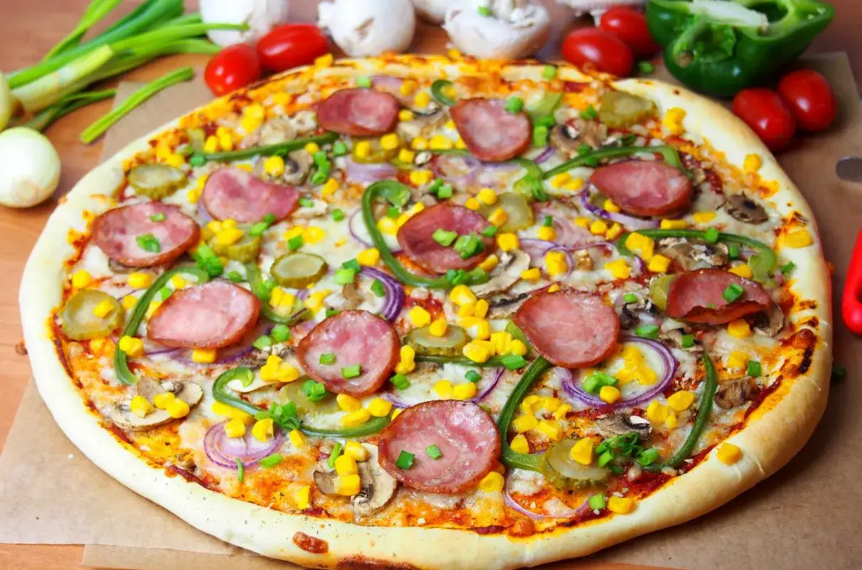 Pizza wiejska składniki: kiełbasa, kukurydza, ogórki kiszone, pieczarki, cebula, papryka.