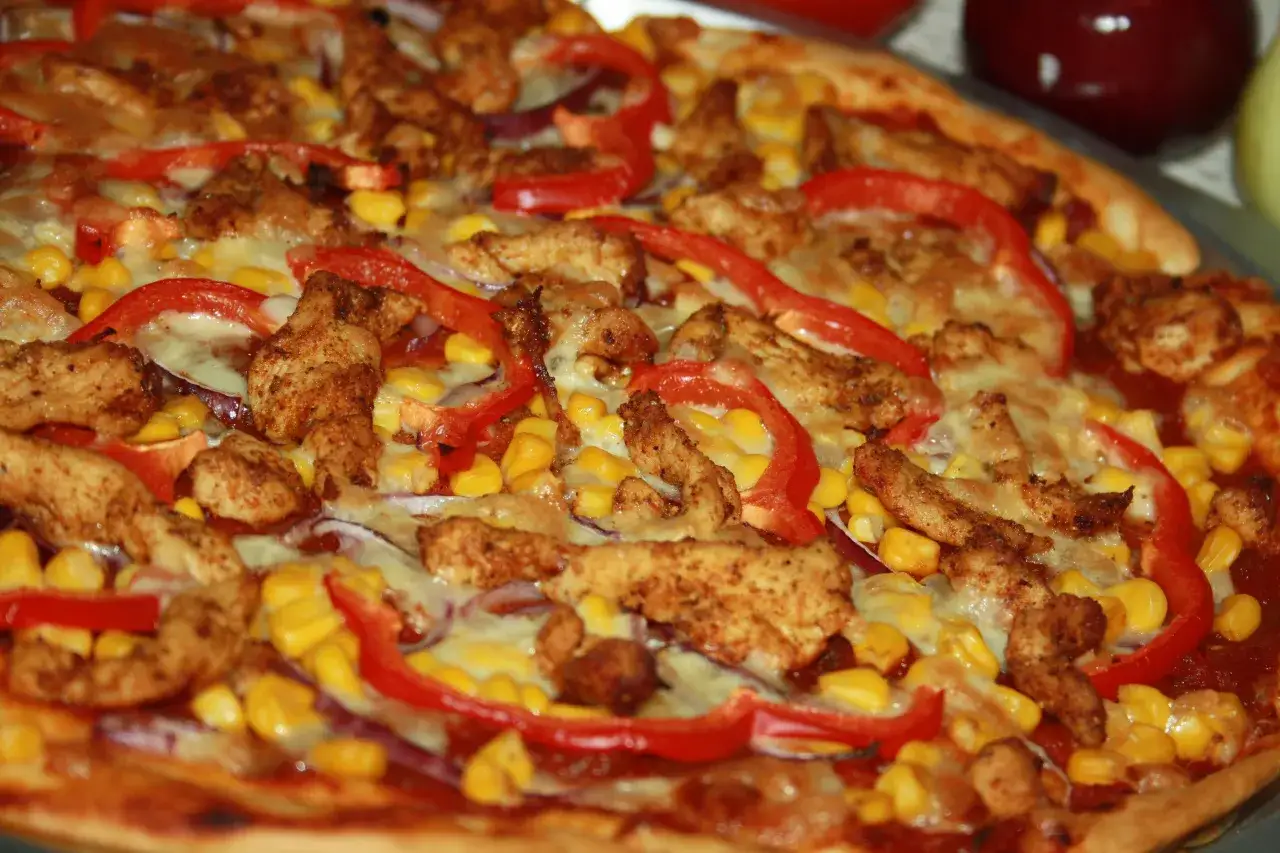 Pyszna pizza z kurczakiem, kukurydzą i papryką, posypana ciągnącym się serem. Idealna na szybki obiad.