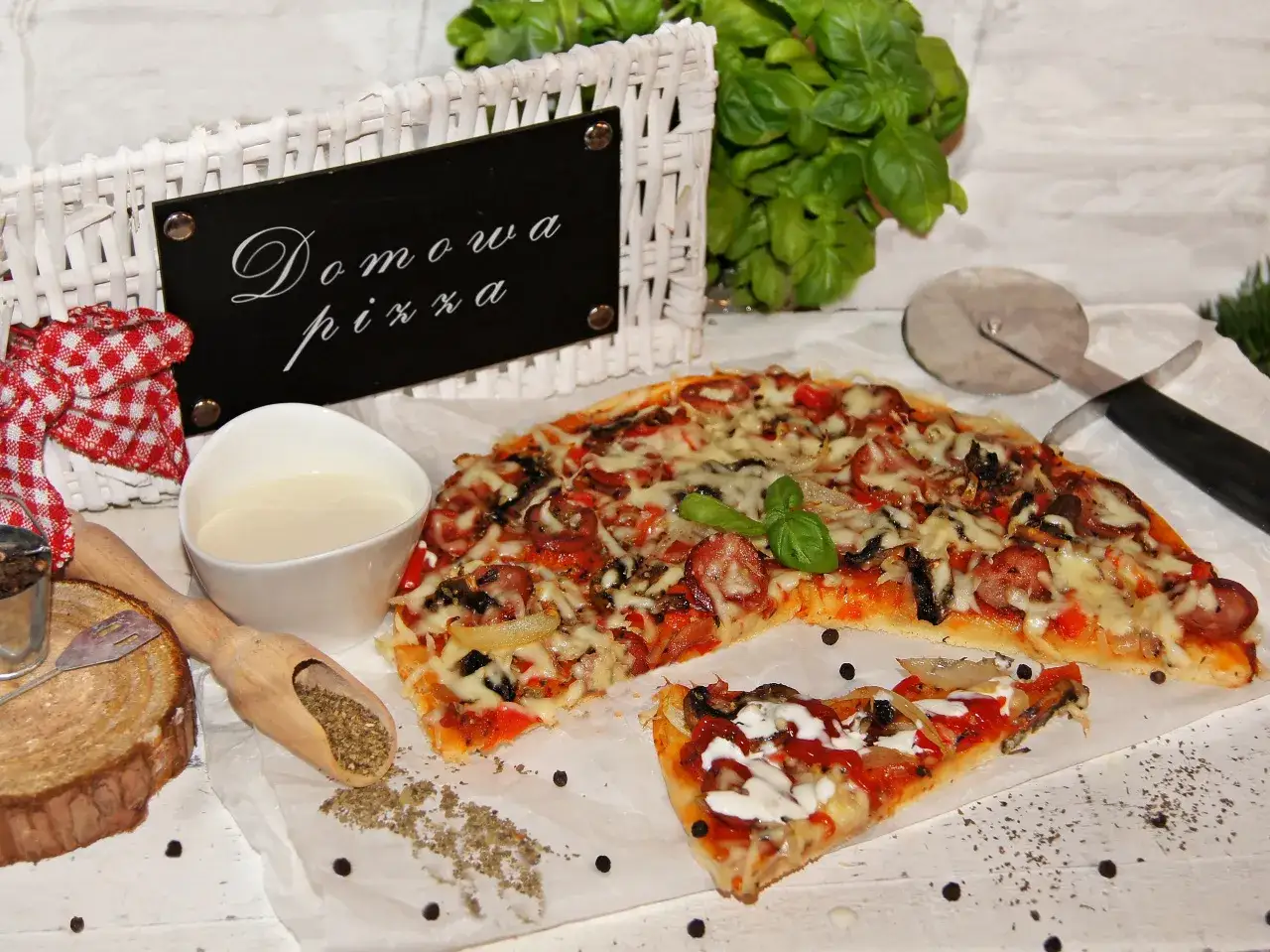 Domowa pizza bez drożdży, z kiełbasą i warzywami, gotowa do podania. Obok sos i zioła.