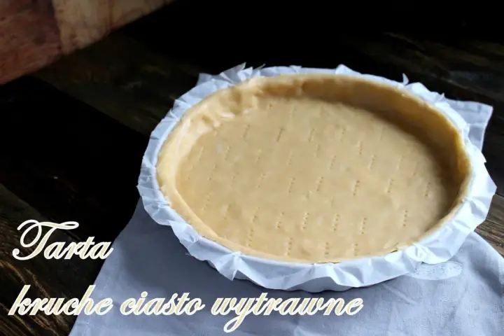 Surowe ciasto kruche wytrawne na tartę, przygotowane do pieczenia. Widelcem nakłute dno i boki.
